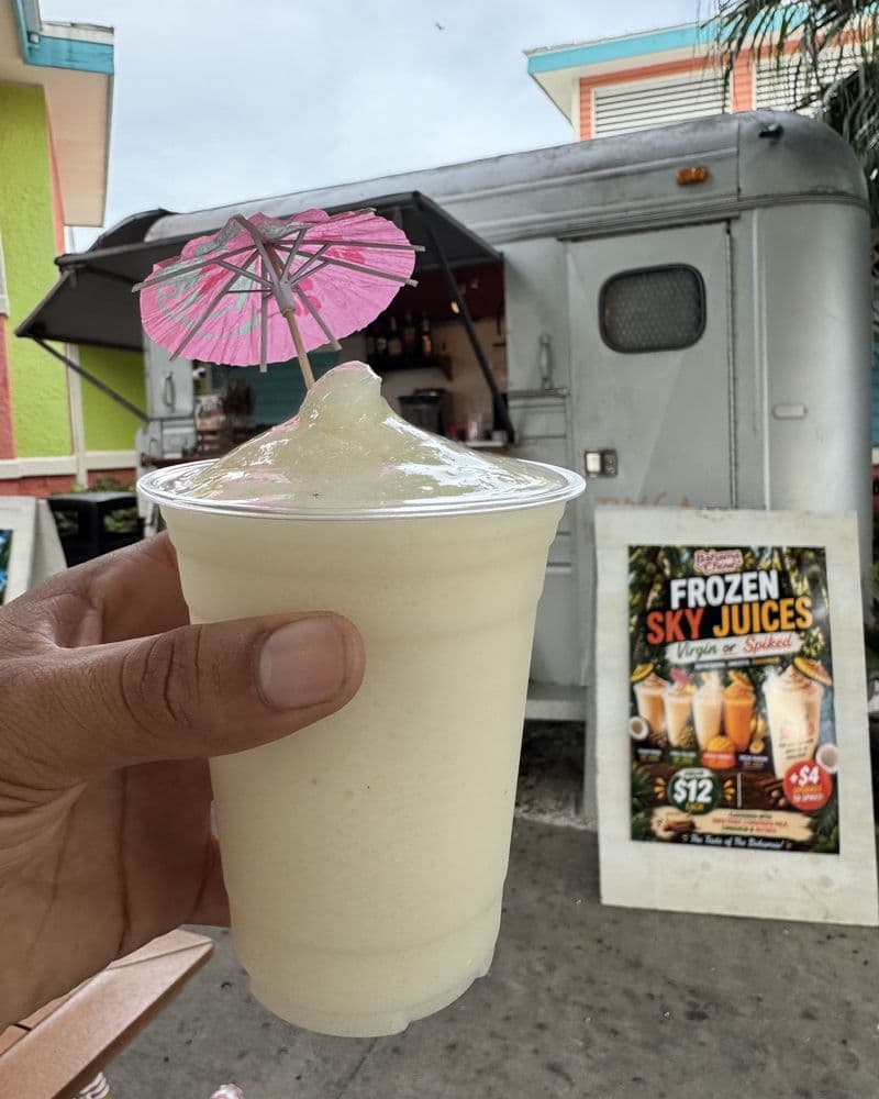 A frozen daiquiri with a paper umbrella, held at the truck window